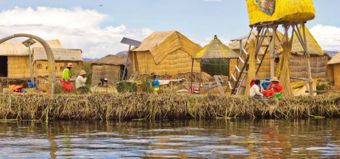 Imagem que mostra comunidade do Lago Titicaca em ilha feita de totora (planta do lago), apresentando crianças próximas a cabanas e embarcação tradicional do lago.
